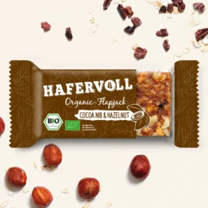 HAFERVOLL Organic Flapjack Cocoa Nib & Hazelnut 60g – Riegel in der Verpackung mit Haselnüssen und Haferflocken